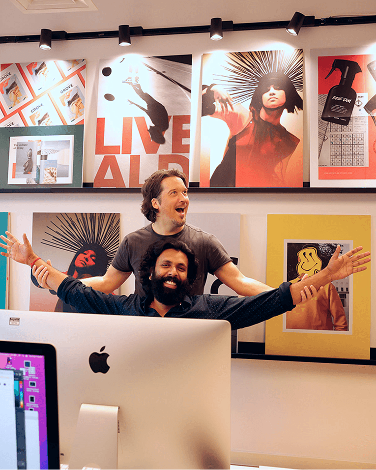 M+C Saatchi Employees smiling in the office with arms raised.
